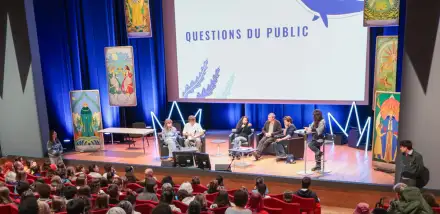 Photo de l'auditorium, des intervenants sur scène, un fond de scène mentionne "questions du public"