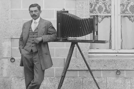 Un photographe pose à côté de son appareil