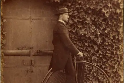 L'homme se tient à la porte pour ne pas tomber. Les roues de ces grand bi font parfois jusque 2,20m ! Il est donc bien impossible de rester sur la selle à l’arrêt