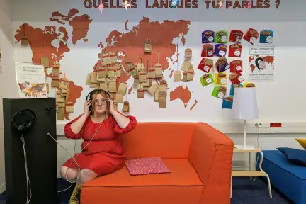 Photo de Louise assise sur un canapé, avec un casque d'écoute sur les oreilles