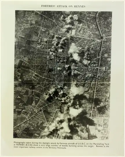 Photographie aérienne de Rennes prise lors de l’attaque aérienne de jour, le 8 mars 1943, par les bombardiers américains – Marque du Domaine Public – Collection Musée de Bretagne, Rennes Photographie aérienne en noir et blanc montrant la ville de Rennes vue du ciel lors d’une attaque aérienne en plein jour, le 8 mars 1943. De nombreuses explosions et panaches de fumée sont visibles à différents endroits, principalement autour du centre de tri ferroviaire. La ville est quadrillée par des rues et des bâtiments visibles malgré la fumée. En haut de l’image figure le titre "FORTRESS ATTACK ON RENNES", et en bas, une légende : "Photographs taken during the daylight attack by Fortress aircraft of U.S.B.C. on the Marshalling Yard at RENNES (8.3.43) show a very large number of bombs bursting across the target. Rennes is the most important railway centre in the Brittany Peninsula."