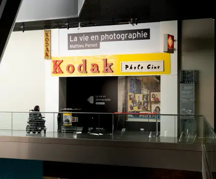 Entrée de l'exposition La vie en photographie de Mathieu Pernot, présentée au Musée de Bretagne aux Champs Libres. Plusieurs enseignes Kodak y sont disposées à l’avant.